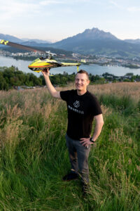 Pascal Beyeler hält einen Moselflug-Helikopter über seinen Kopf. Er trägt ein schwarzes T-Shirt mit dem MountOn Logo und Schriftzug auf der Brust.