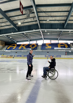 Foto mit Kevin Meier und Stephan Gmür, die auf dem Eisfeld sind und zur Tribüne zeigen.